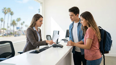 Young driver standing by a modern car hire vehicle on a sunny, palm-lined street in Los Angeles