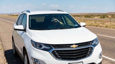 A radar detector on the dashboard of a car rental driving down a long, open highway in Texas