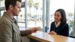 Close-up of a person holding a cracked driving licence at a car rental counter in California