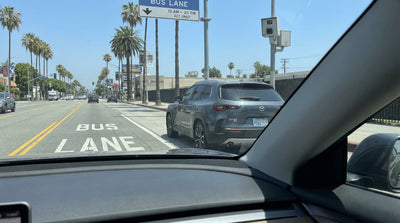 A car hire driving in a red bus-only transit lane on a multi-lane street in Los Angeles