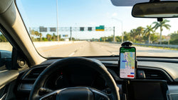 Person holding a smartphone with a map open outside a Florida car rental lot on a sunny day