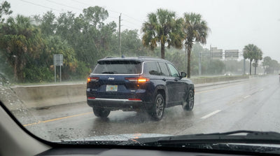 A car rental driving through a heavy downpour on a multi-lane highway in Florida