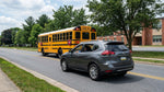 Driver's view from a car hire stopped behind a yellow school bus with flashing lights on a suburban Pennsylvania street