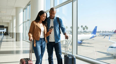 A traveler with luggage waits for a car hire shuttle bus at the busy LAX curbside in Los Angeles