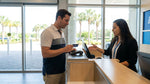 A customer at a car hire desk in Orlando airport holding a credit card to pay for their vehicle