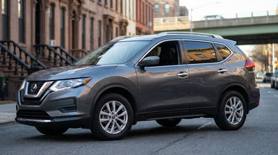 A black car hire SUV approaches a low overpass on a tree-lined parkway in New York