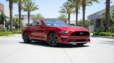 A white convertible car rental driving along a sunny coastal highway in California