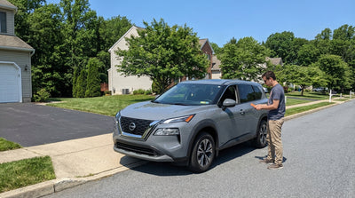 A car rental with a parking ticket on the windshield is blocking a driveway on a residential street in Pennsylvania