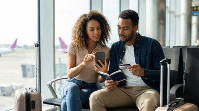 A woman with luggage walks towards a row of cars at a sunny California airport car rental lot