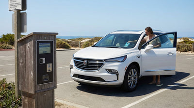 A sunny California beach car park with a car rental parked in a bay overlooking the blue Pacific Ocean