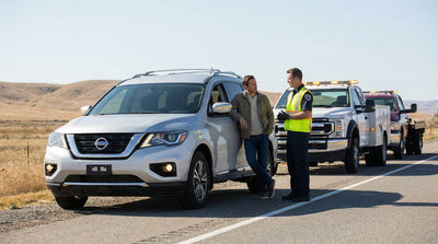 A person on the phone beside their broken-down car hire on a quiet country road in the United Estates