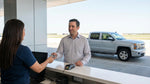 A driver holds a business debit card to pay for a car rental deposit at an airport counter in Texas