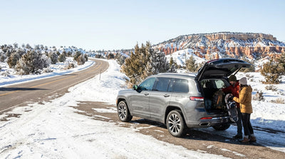 A silver car hire on a desert highway driving away from the Las Vegas skyline under a clear blue sky