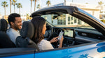 A person sits in the driver's seat of their California car rental, connecting a phone to the dashboard screen