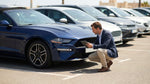 Person inspecting the exterior of a white SUV in a Texas car rental lot