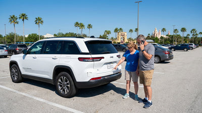 A white SUV car hire parked in a row at a large, sunny Orlando theme park parking lot