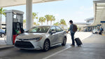 Close up of a person refueling a white car rental at a gas station near Orlando Airport