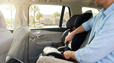 A parent struggles to install a child car seat in the back of an Orlando car rental