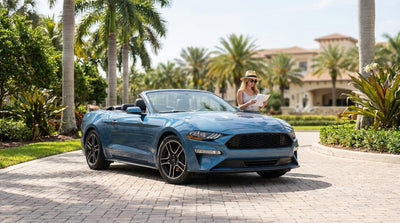 A convertible car rental driving down a scenic, palm-lined coastal highway in Florida