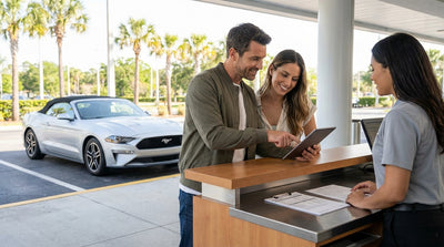 A convertible car hire driving down a sunny highway lined with palm trees in Orlando