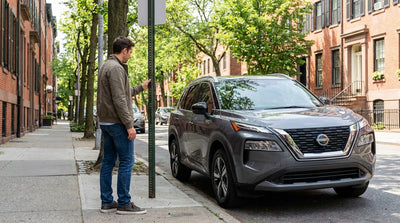 A silver car rental parked next to a time-limit street sign on a city block in Pennsylvania