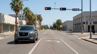 A modern car hire stopped at a red traffic light on a busy city street intersection in Texas