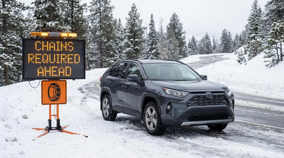 A car rental driving on a winding, snow-covered mountain road in a California forest