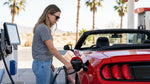 A person refueling their car hire at a gas station with the neon lights of the Las Vegas Strip in the background