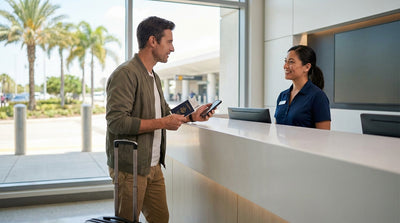 A person at a car rental counter in the Orlando airport hands their documents to an agent to pick up their keys