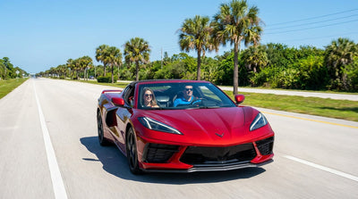 A white car rental convertible driving down a sunny, palm-lined street in Orlando, Florida