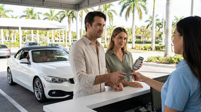 A person at a counter handing over a credit card to an agent for a car rental in Miami