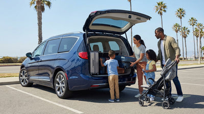 A family loading suitcases into the trunk of their SUV car rental on a sunny coastal drive in California