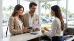 Smiling couple holding keys next to a white convertible car rental on a sunny street in Miami