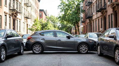 Compact car rental driving down a busy New York street lined with tall buildings