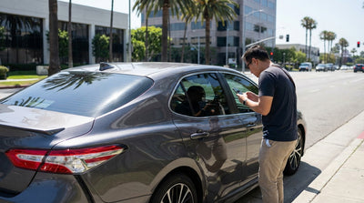 A modern car hire with dark tinted windows parked on a sunny coastal highway in California