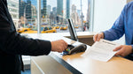 Customer handing a credit card to an agent at a car hire desk in New York