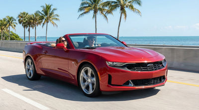 A white convertible car rental driving on a scenic coastal highway in Florida with palm trees and turquoise water