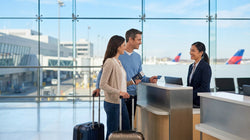Passengers with suitcases standing at a car hire counter inside Philadelphia Airport in Pennsylvania