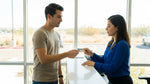 Young driver showing a driving licence to an agent at a car rental counter in Texas