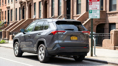 A car hire parked next to a permit parking sign on a residential street in New York