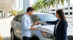 Driver in a car rental passing under an electronic toll gantry on a highway in Miami
