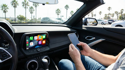 A person connects their phone to the screen of a modern car rental on a sunny day in California
