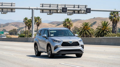 A car rental drives on a sunny Los Angeles freeway under an electronic cashless toll gantry with light traffic