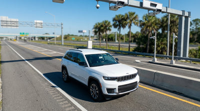A car hire drives on a highway under a large green toll sign in sunny Orlando, Florida