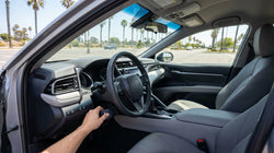 Driver operating steering wheel hand controls inside a car hire on a sunny coastal road in California