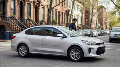 A modern car rental drives down a busy street lined with yellow taxis and skyscrapers in New York