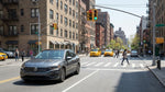 A car hire turning left at a busy New York City intersection under a green arrow traffic light