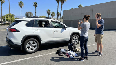 A silver car rental parked on a sunny California street with an open trunk revealing packed luggage inside