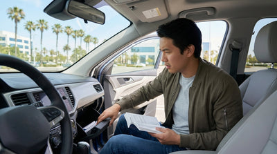A driver searches the open glove compartment of their car hire on a sunny California roadside