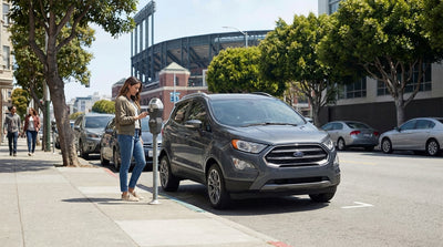 A modern car hire drives past Oracle Park on a busy street in San Francisco